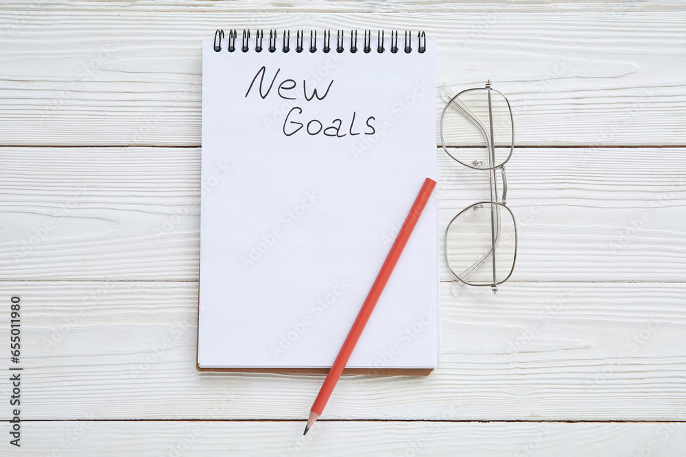 Notebook with empty to do list, pencil and eyeglasses on white wooden background. New year goals