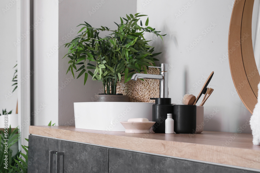 Sink bowl and bath accessories on wooden counter in bathroom