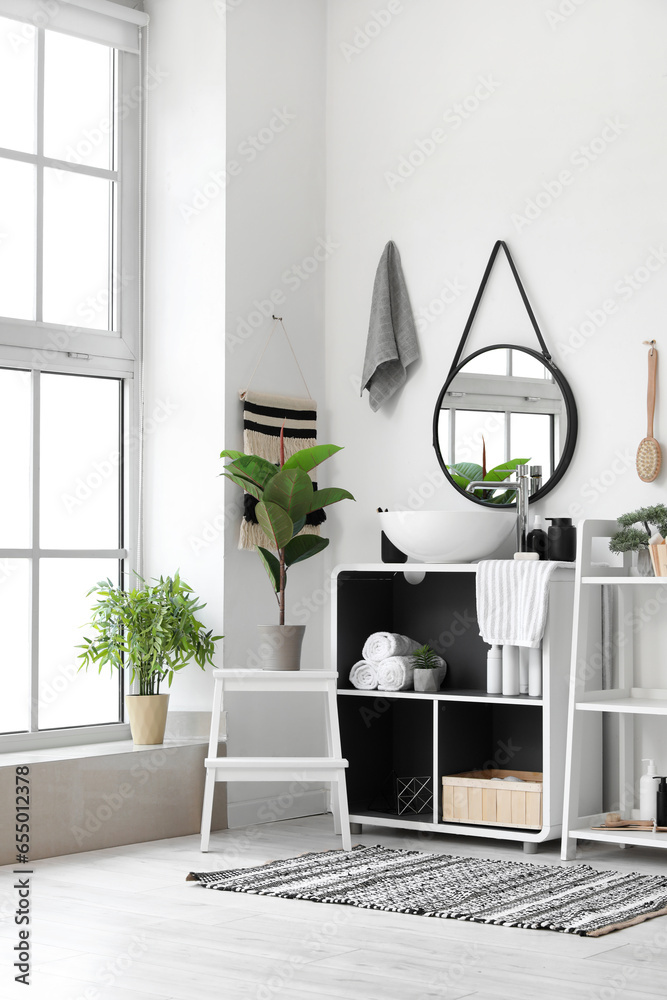 Interior of light bathroom with sink bowl, bath accessories and shelving units