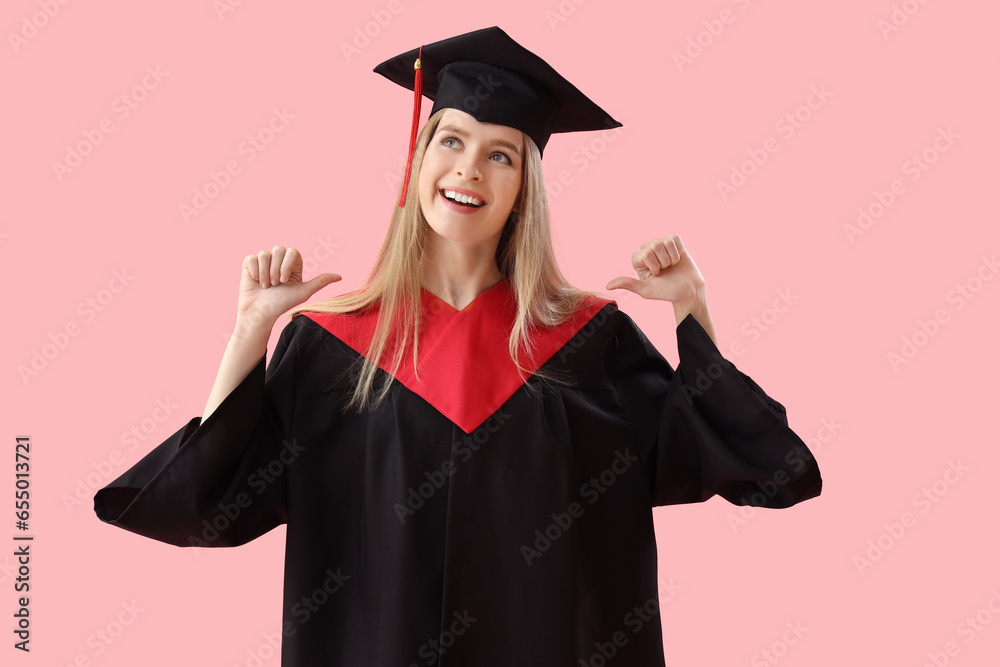 Female graduate student pointing at herself on pink background