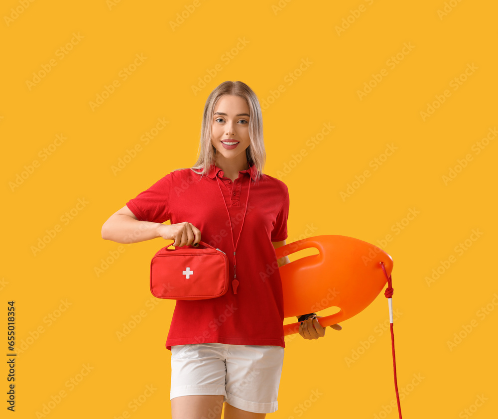 Female lifeguard with rescue buoy and first aid kit on yellow background