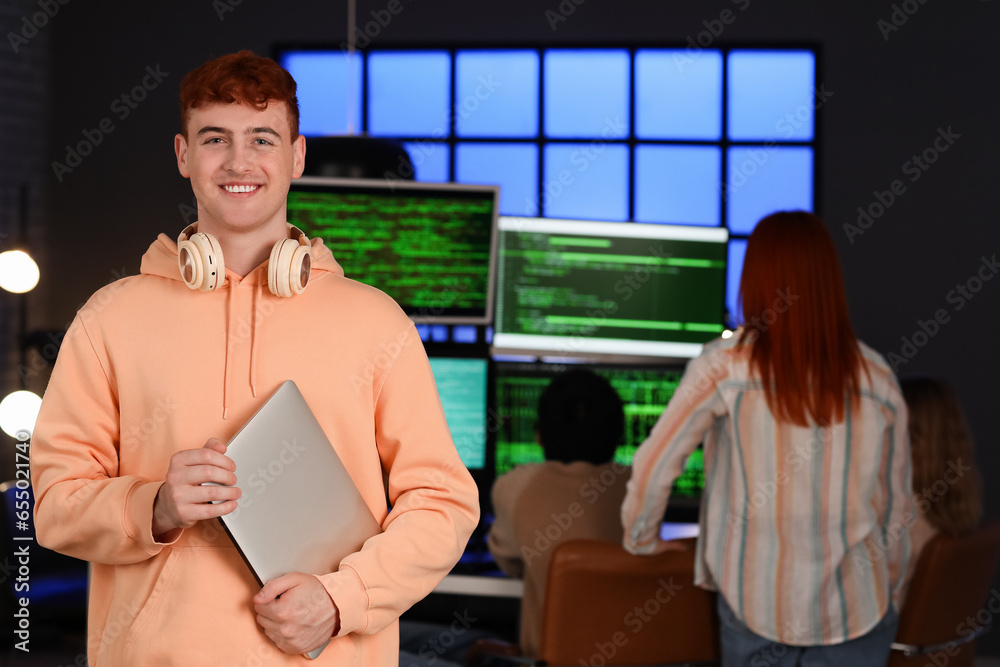 Male programmer with laptop in office at night