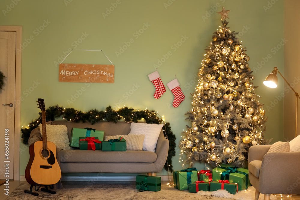 Interior of living room with Christmas tree, glowing lights, grey sofa and guitar