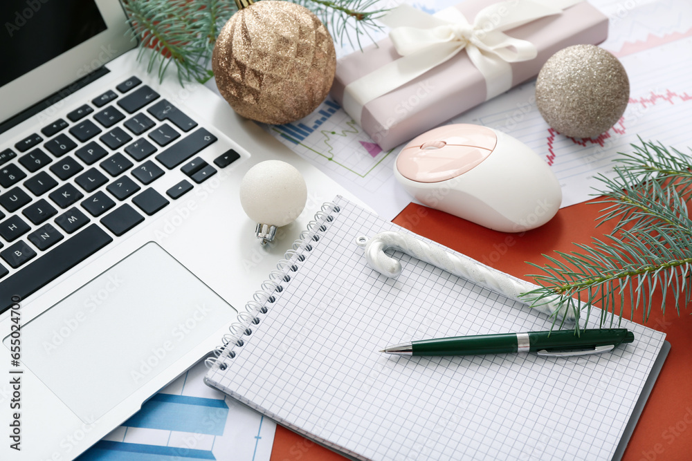 Laptop with office supplies and Christmas decor on brown background, closeup