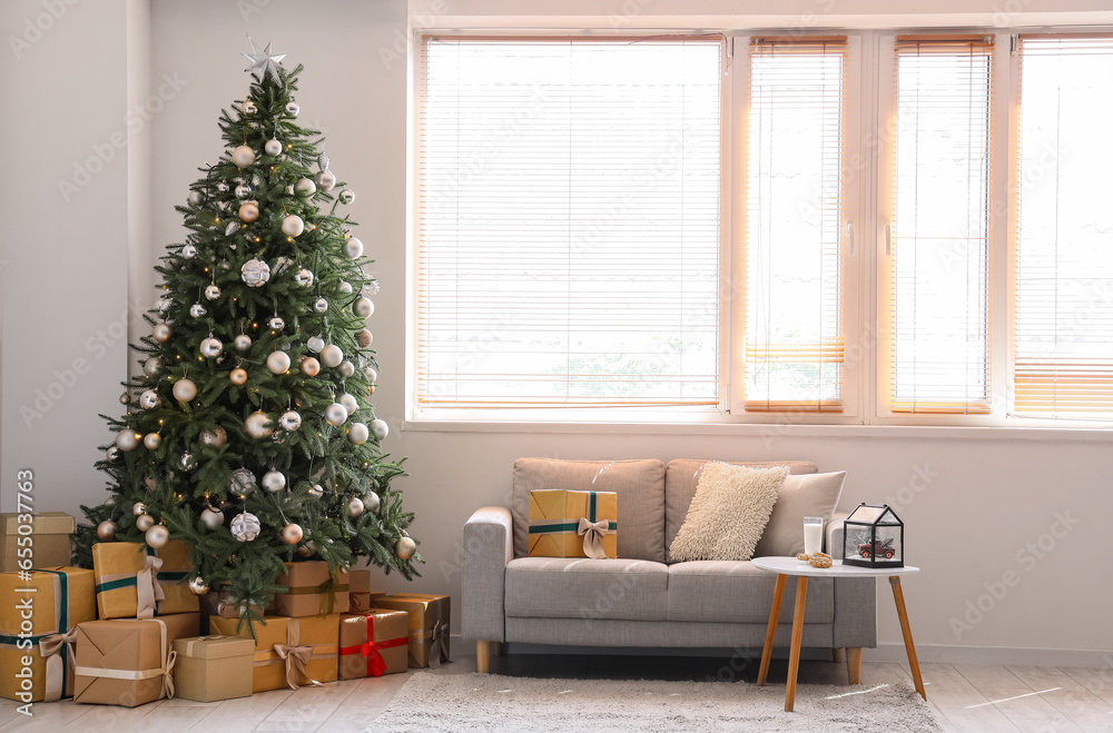 Interior of festive living room with grey sofa and gift boxes under Christmas tree