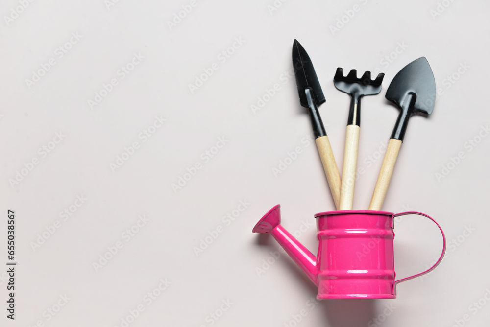 Watering can with gardening rake and shovels on white background