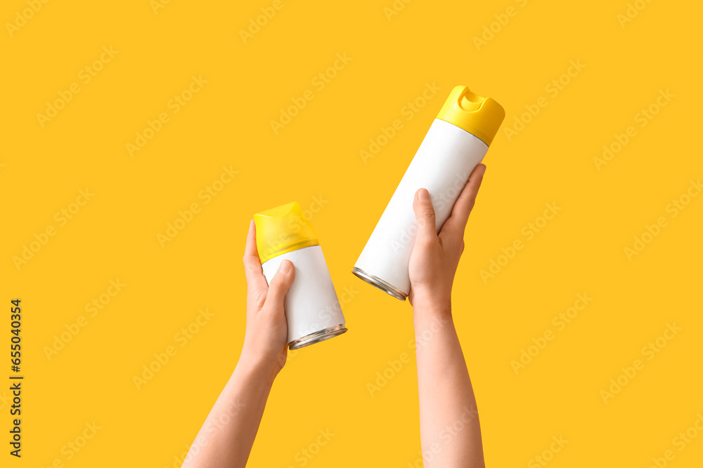 Woman with cleaning supplies on yellow background