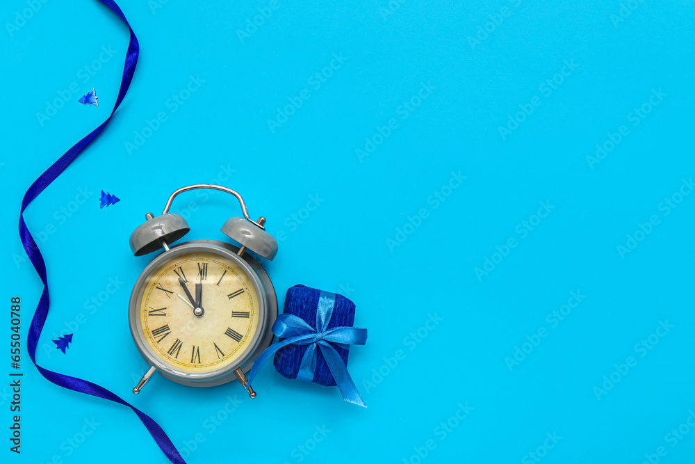 Alarm clock with Christmas gift box and ribbon on blue background