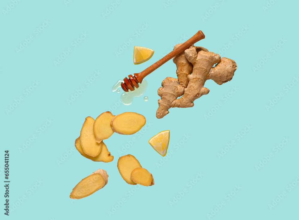 Flying slices of fresh ginger root and dipper with honey on blue background