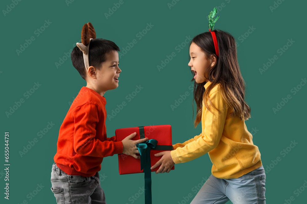 Cute little children with Christmas gift on green background