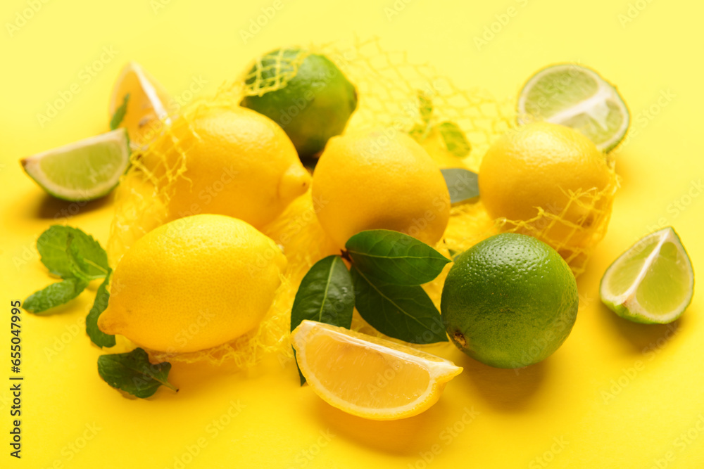 Mesh bag with fresh lemons and limes on yellow background