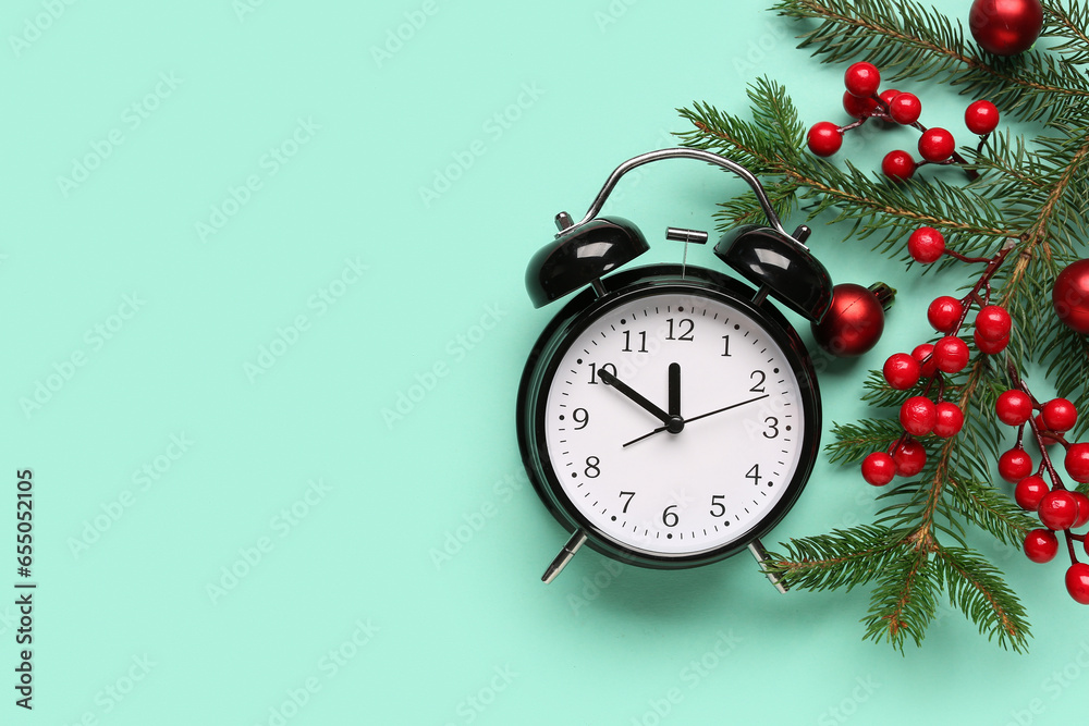 Alarm clock and Christmas tree branches with balls on turquoise background