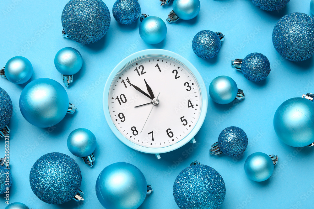 Alarm clock with Christmas balls on blue background