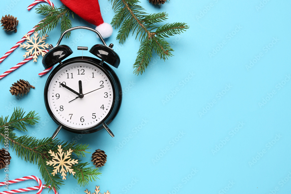 Alarm clock with Christmas tree branches, snowflakes and candy canes on blue background