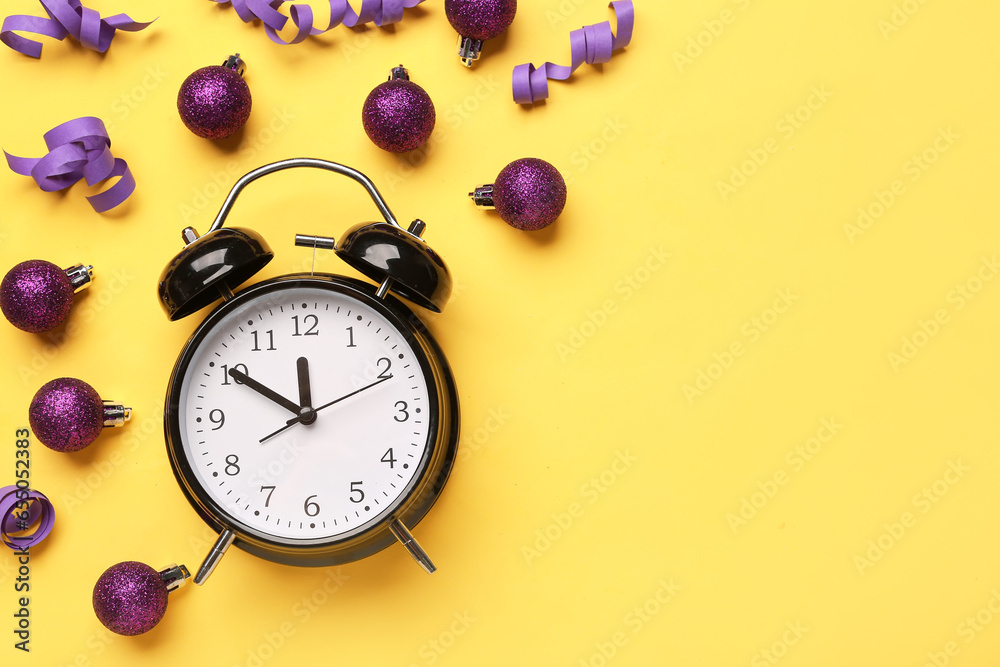 Alarm clock with Christmas balls on yellow background