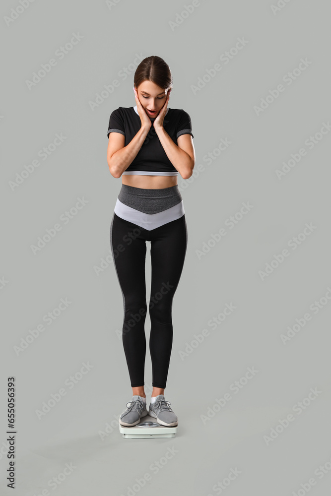 Shocked young woman with scales on grey background. Weight loss concept