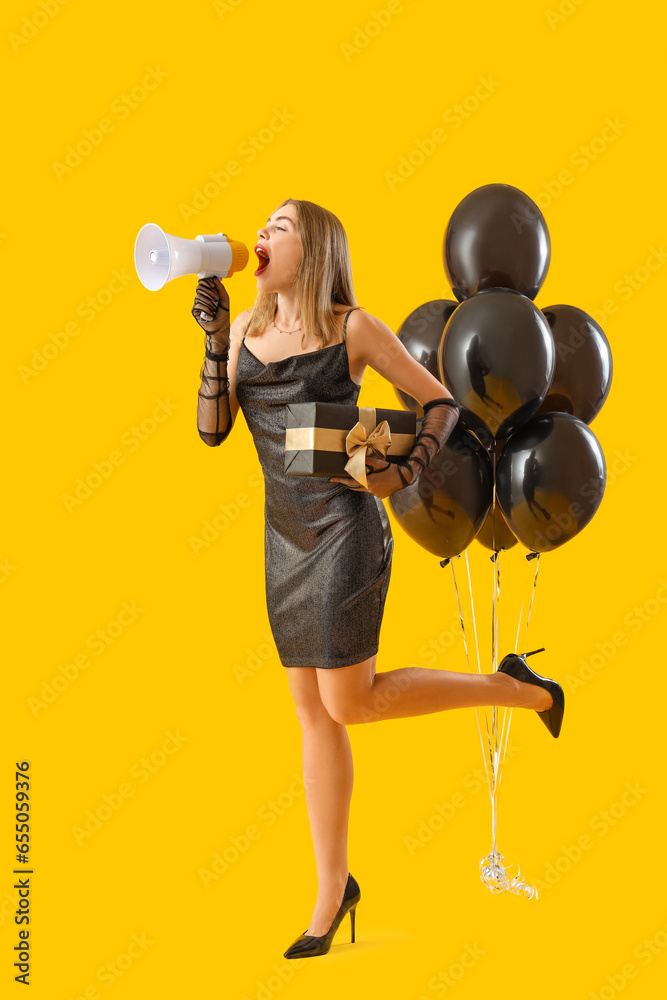 Young woman with gift shouting into megaphone on yellow background. Black Friday sale