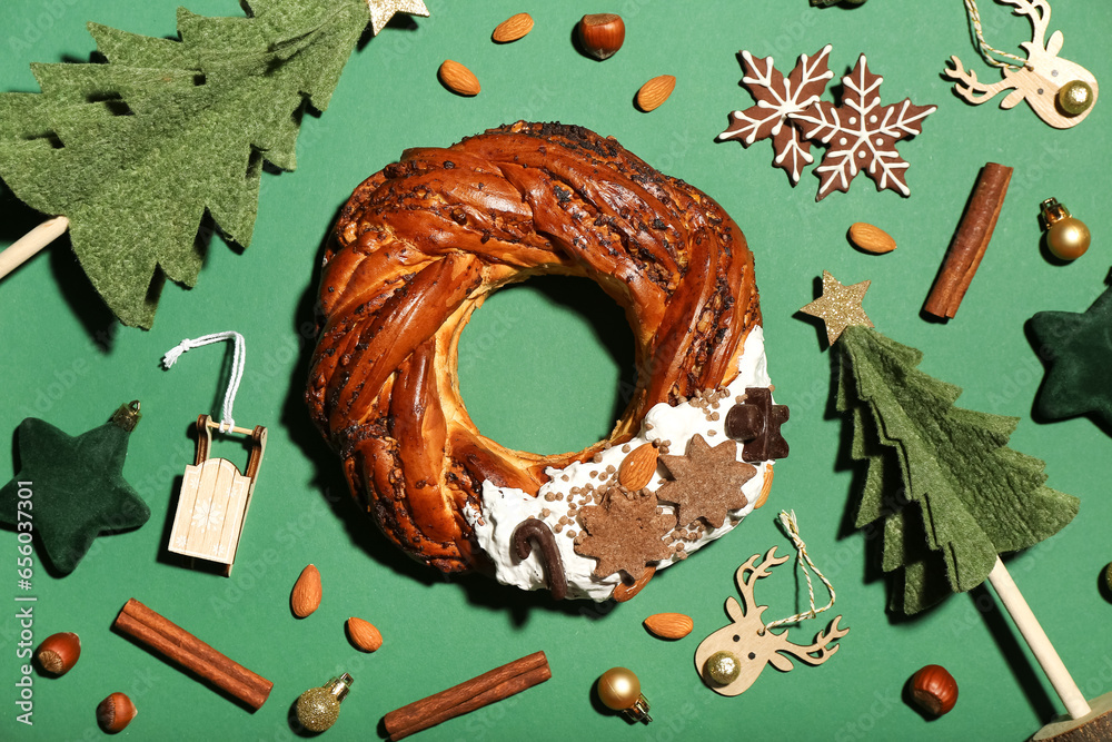 Composition with tasty Christmas pastry wreath, decorations, spices and nuts on green background