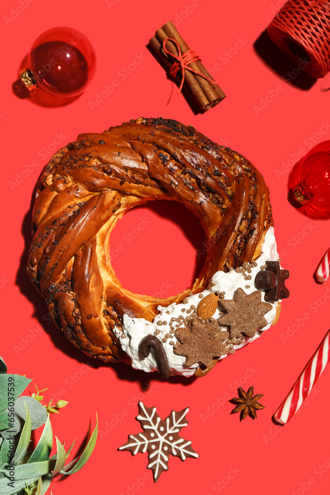 Tasty Christmas pastry wreath and decorations on red background