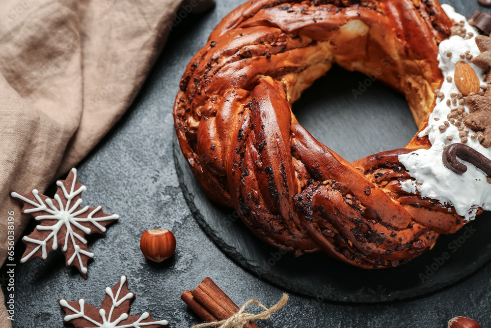 Board with tasty Christmas pastry wreath and cookies on dark background, closeup