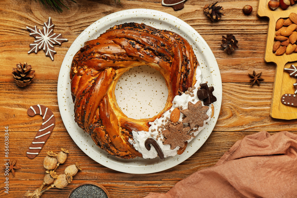 Plate with tasty Christmas pastry wreath, cookies and cones on wooden background