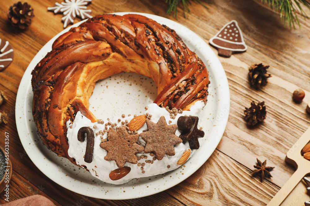 Plate with tasty Christmas pastry wreath on wooden table, closeup