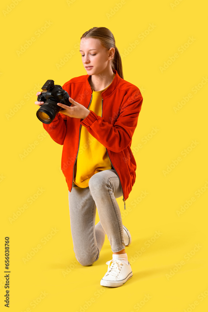 Female student with photo camera on yellow background