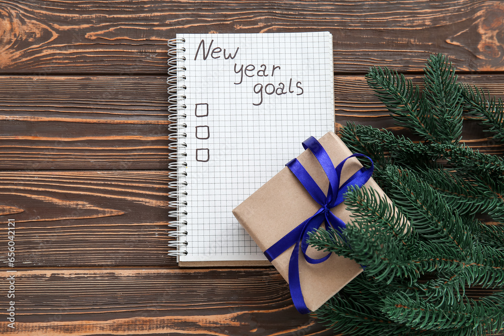 Notebook with empty to do list, gift box and fir branches on wooden background. New year goals