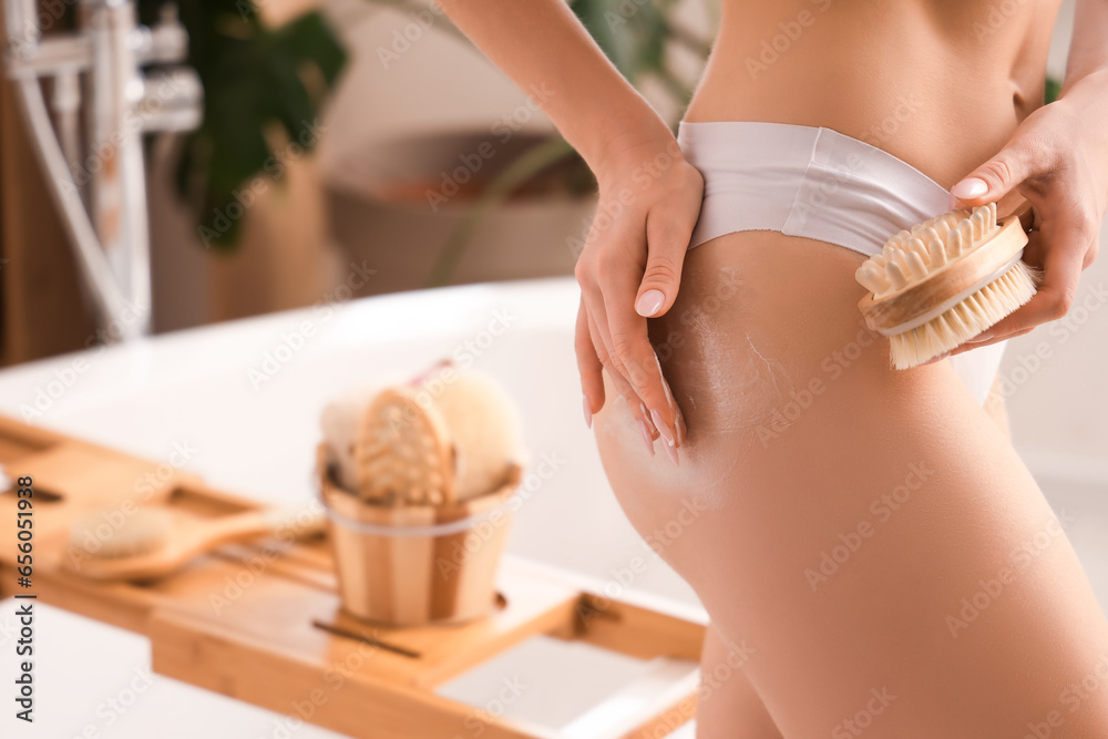 Young woman applying anti-cellulite cream onto her buttocks in bathroom, closeup