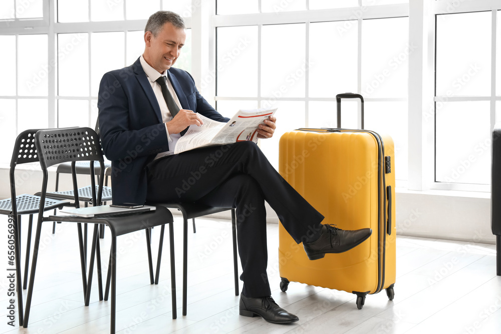 Mature businessman reading newspaper in hall of airport