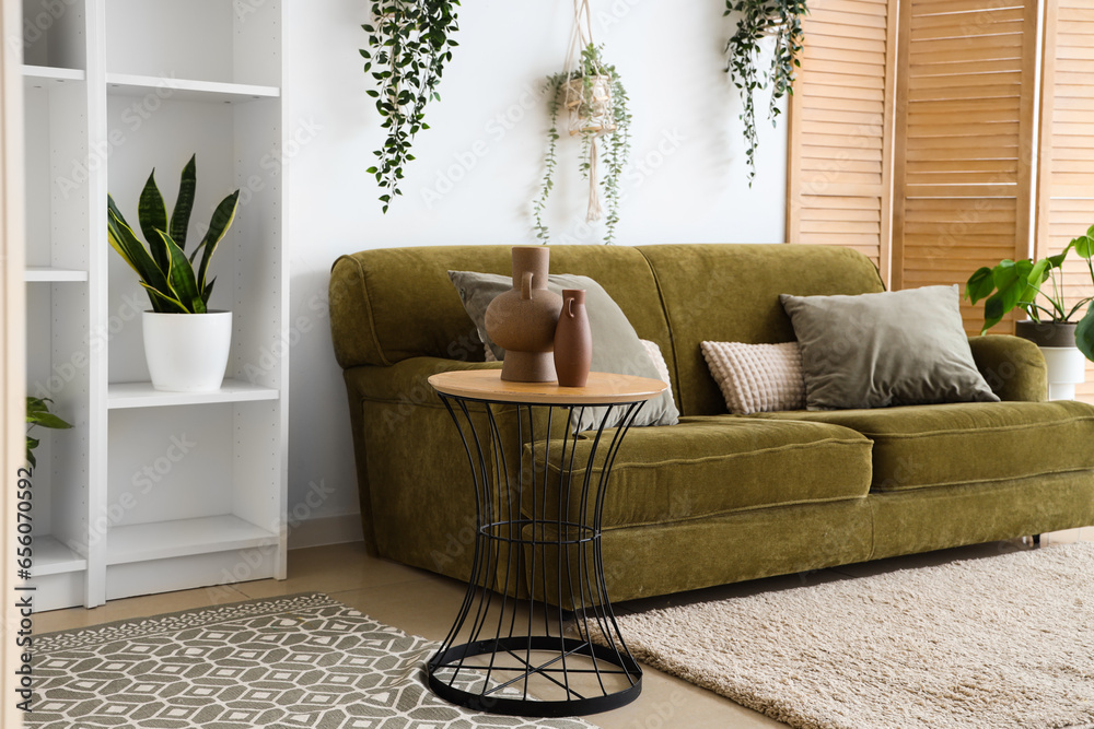 Interior of light living room with green sofa and houseplants