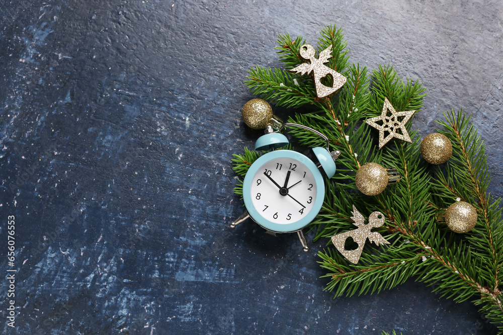 Alarm clock and Christmas tree branches with balls on blue background