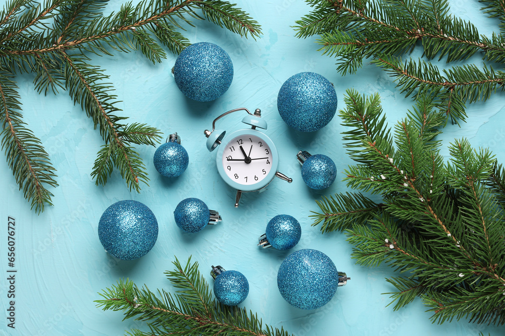 Alarm clock and Christmas tree branches with balls on blue background