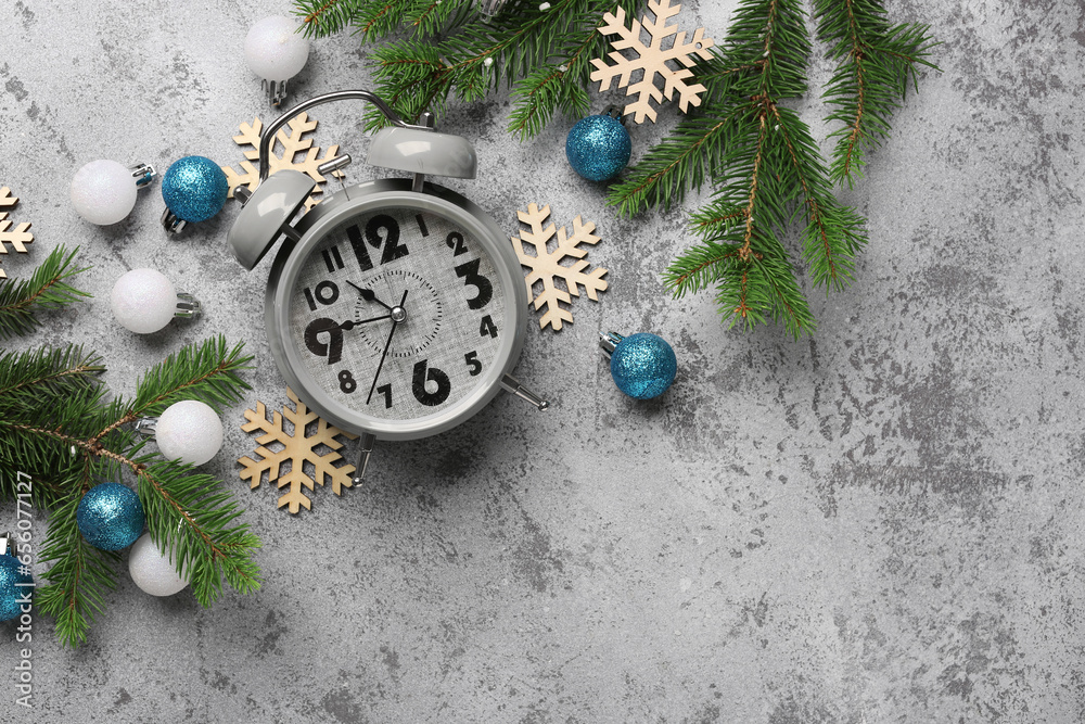 Alarm clock and Christmas tree branches with balls on blue background