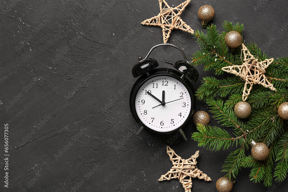 Alarm clock and Christmas tree branches with balls on black background