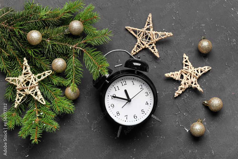 Alarm clock and Christmas tree branches with balls on black background