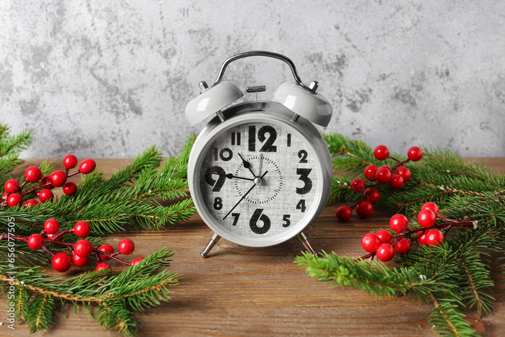 Alarm clock and Christmas tree branches with rowan on wooden table