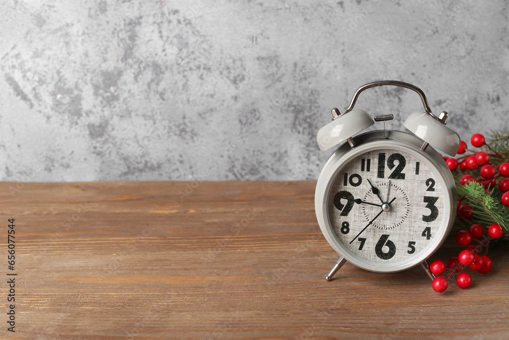 Alarm clock and Christmas tree branches with rowan on wooden table