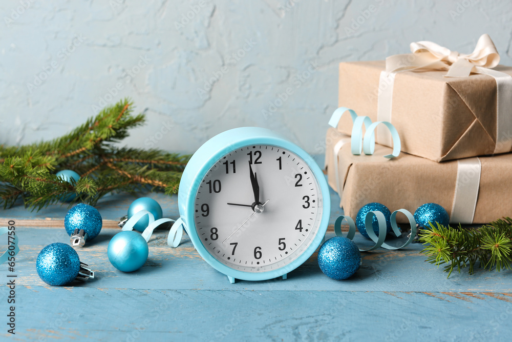 Alarm clock and gift boxes, Christmas tree branches with balls on blue wooden table