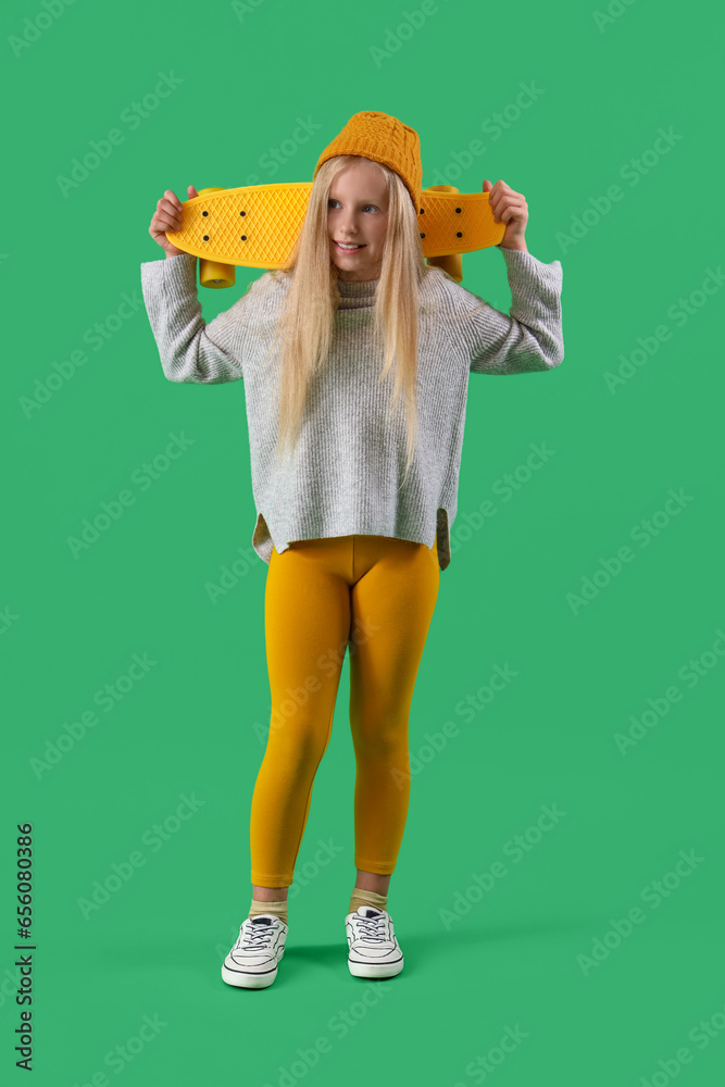 Little girl with skateboard on green background