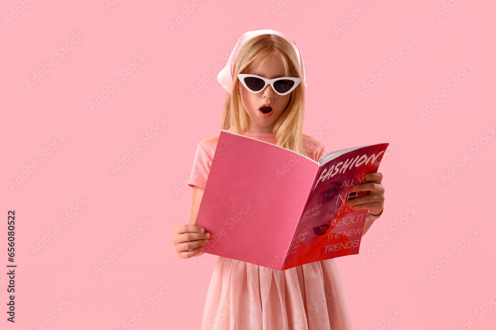 Little girl reading fashion magazine on pink background