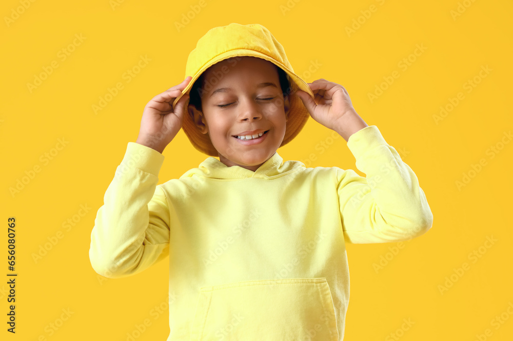 African-American little boy in bucket hat on yellow background