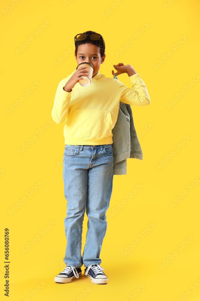 African-American little boy drinking cocoa on yellow background