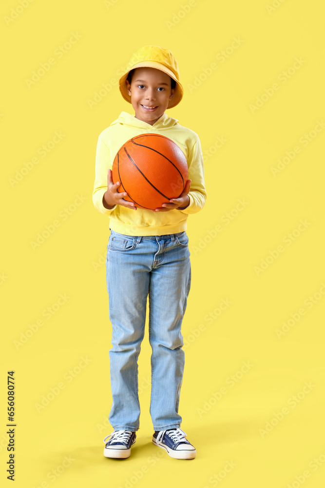 African-American little boy with ball on yellow background