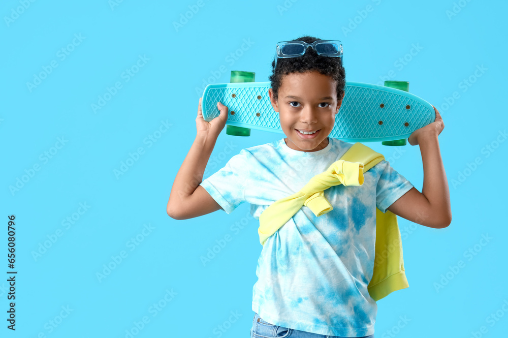 African-American little boy with skateboard on blue background