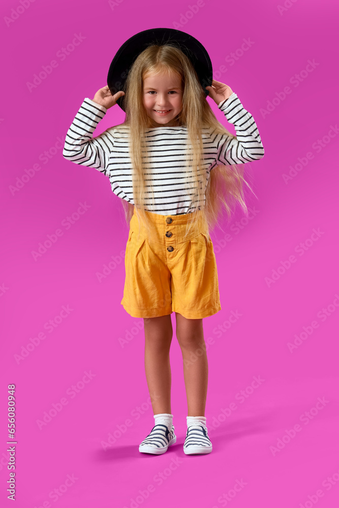 Cute little girl in hat on purple background