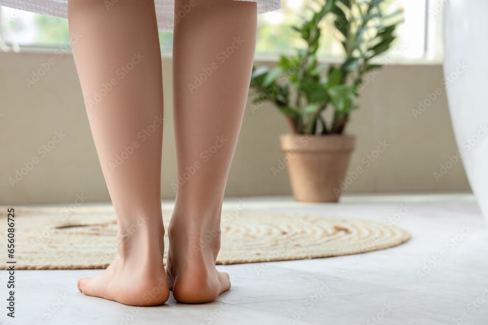 Barefoot woman in bathroom with floor heating, back view