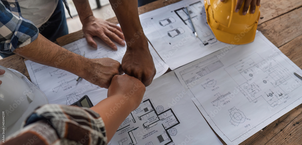 A team of engineers who successfully planned work on a modern home construction project shook hands and congratulated the team on their success.