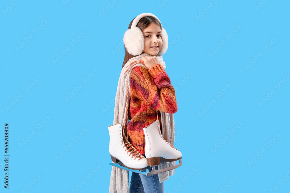 Cute little girl in winter clothes with ice skates on blue background