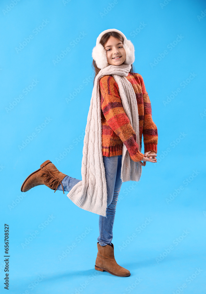 Cute little girl in winter clothes on blue background